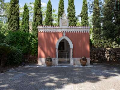 Ma le sorprese non sono finite, visto che sul lato opposto del giardino scoviamo una chiesetta con merlatura bianca e un fastigio goticheggiante con un bassorilievo religioso